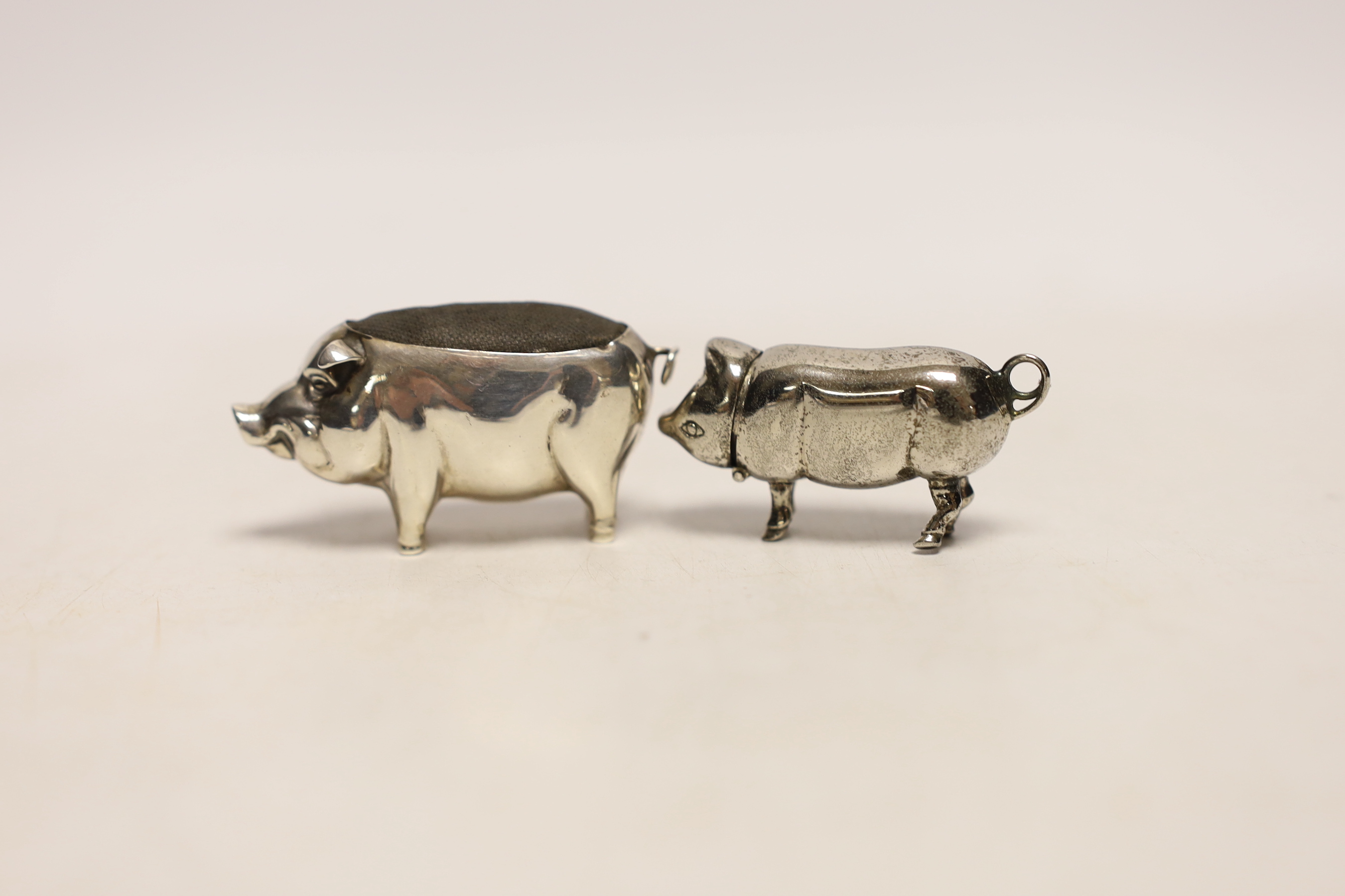 An Edwardian novelty silver pin cushion modelled as a pig, Henry Matthews, Birmingham, 1907, length 53mm, together with a metal box, modelled as a pig with hinged head.